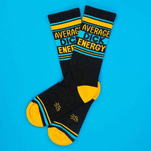 Funny black socks with Average Dick Energy text in yellow and turquoise. Crisscross display on bright blue background.