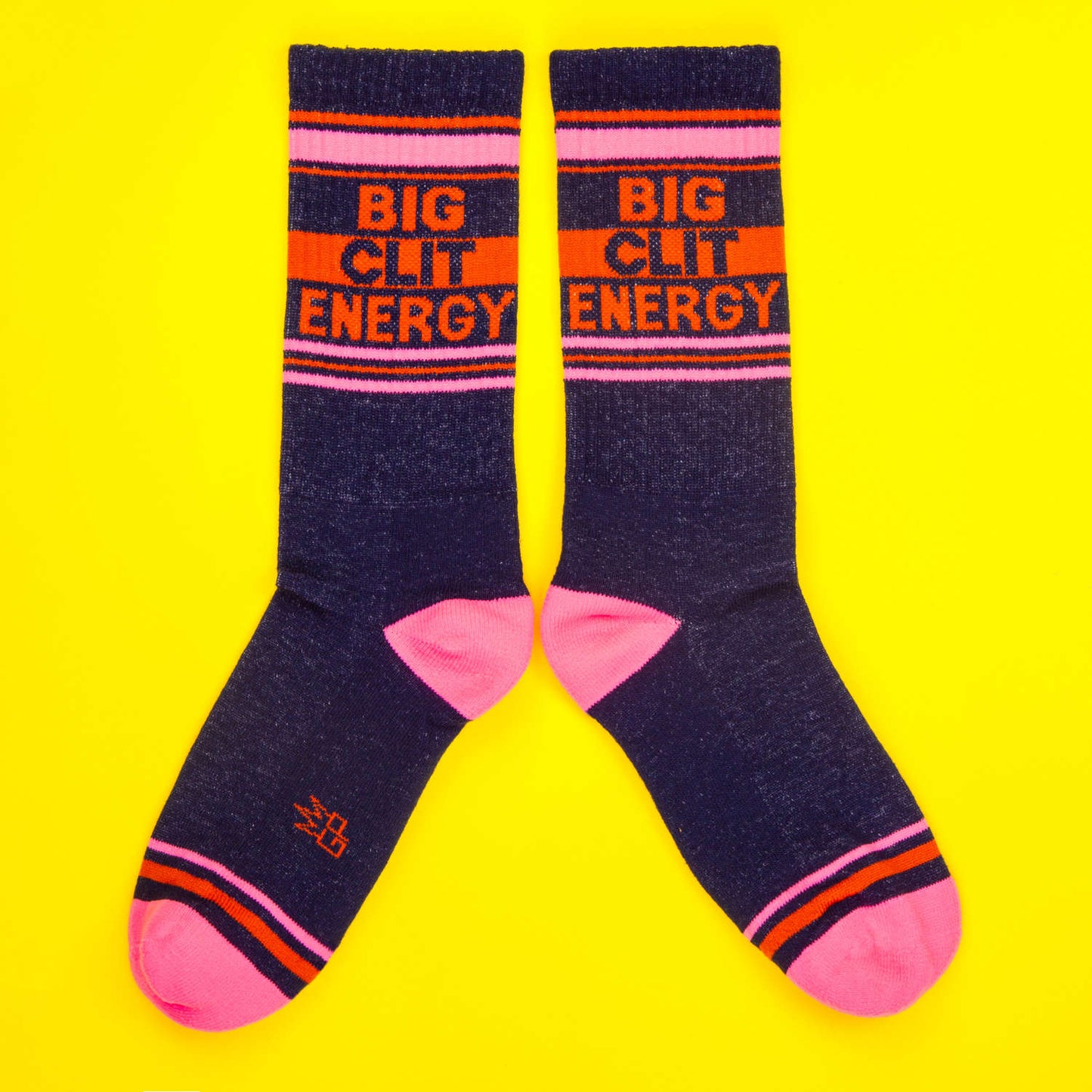 Pair of Navy and pink socks with orange accents on a bright yellow background, reading 'Big Clit Energy' in bold capital letters.