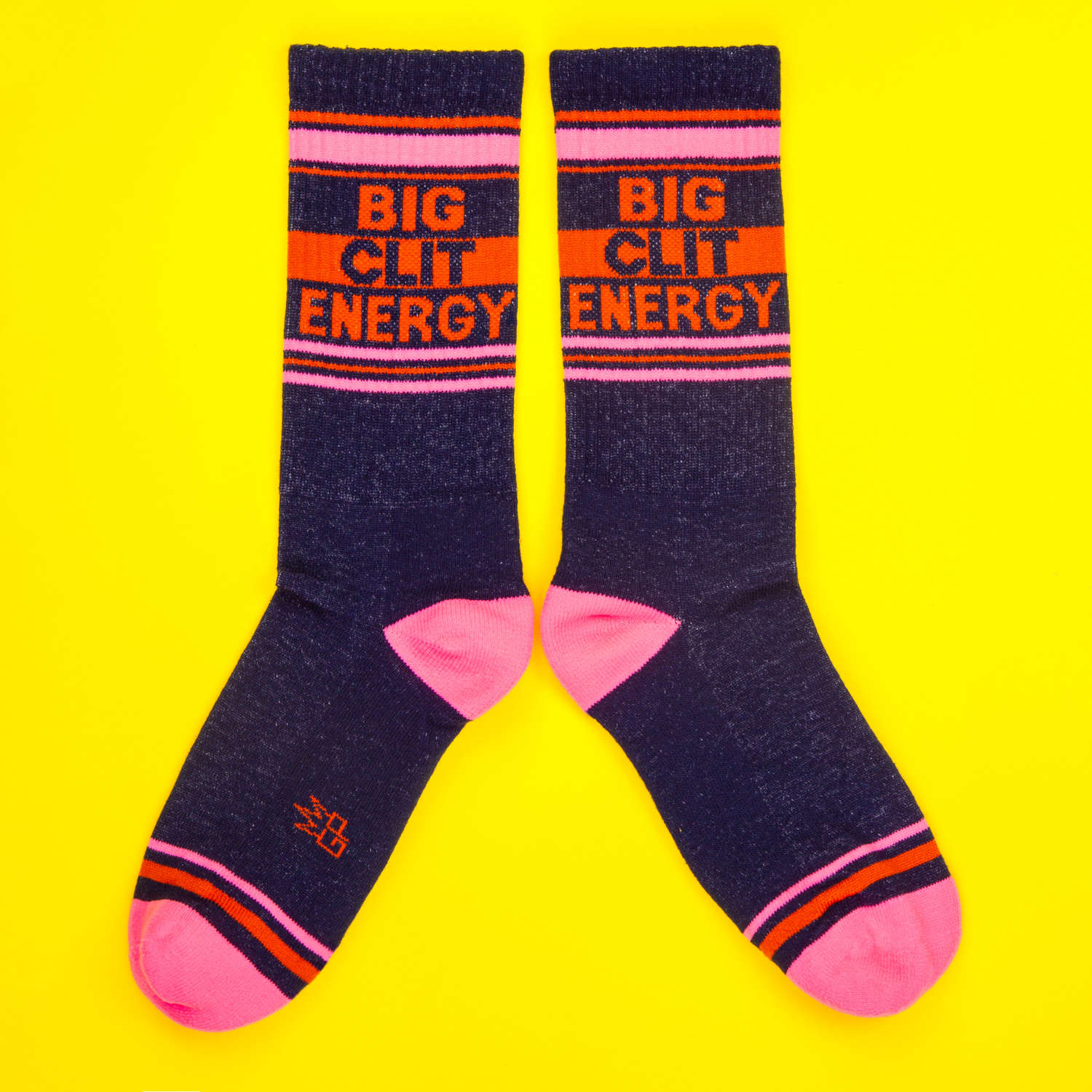 Pair of Navy and pink socks with orange accents on a bright yellow background, reading 'Big Clit Energy' in bold capital letters.