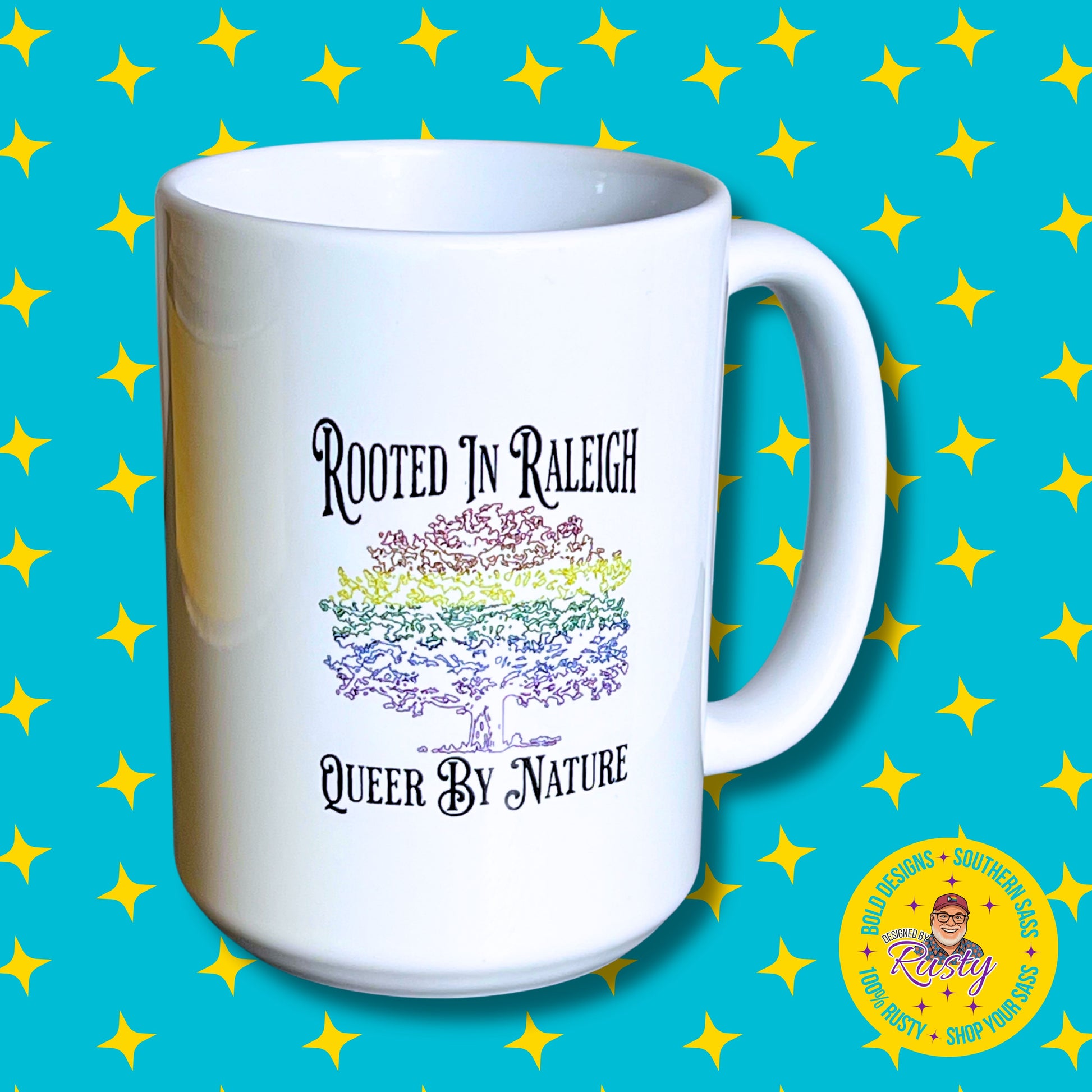 White 15 oz ceramic mug with rainbow oak tree design and Rooted in Raleigh text, on turquoise background with yellow stars and DBR logo.