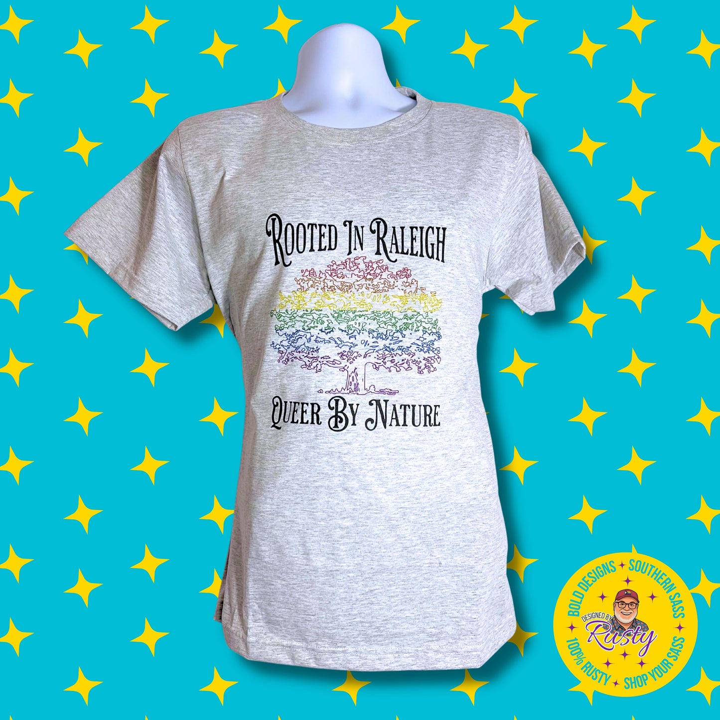 Branded Background - Shopify.jpg
Alt: Light gray T-shirt with rainbow tree and “Rooted in Raleigh – Queer by Nature” text, on turquoise background with yellow stars and DBR logo.