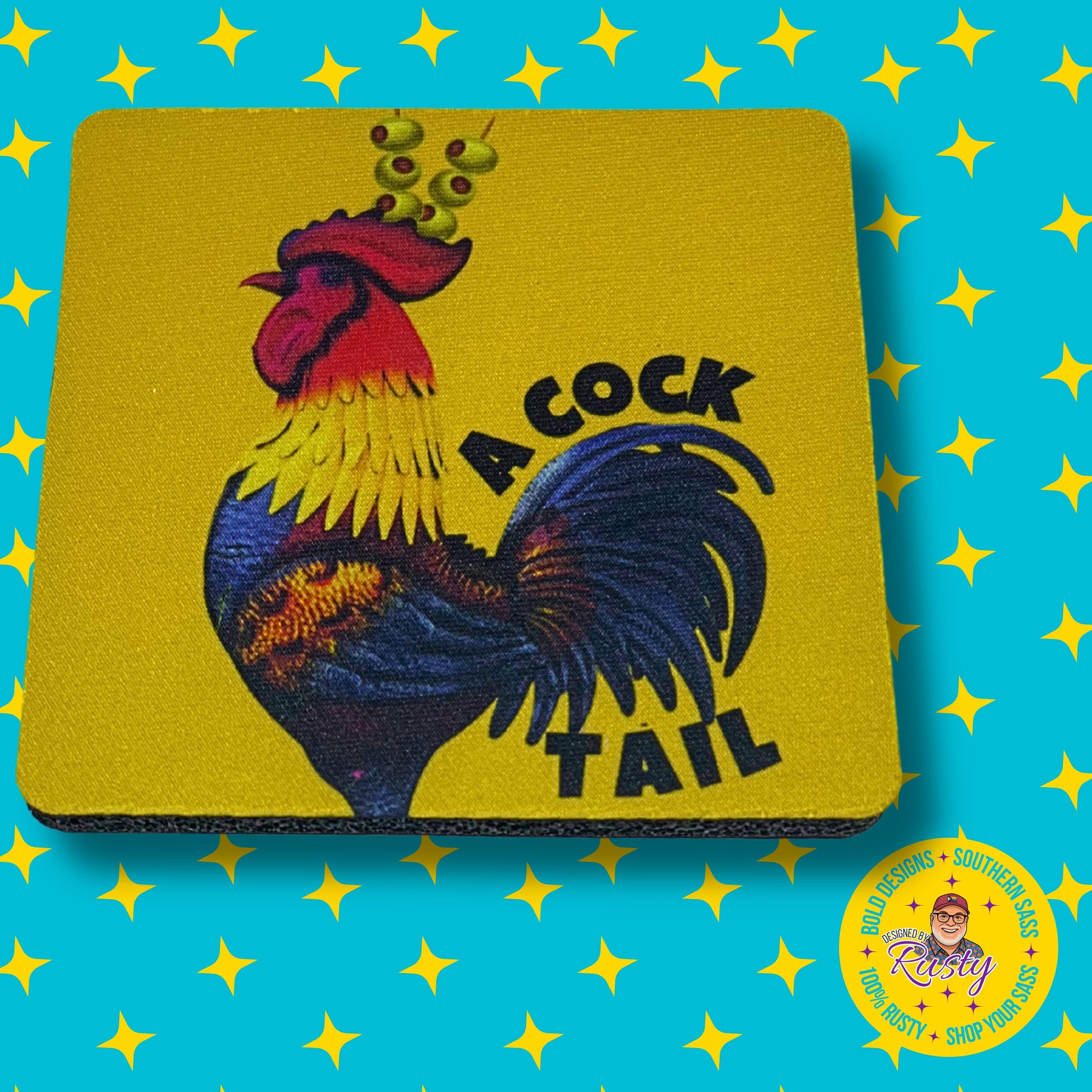 Yellow “A Cocktail” rooster coaster with martini olive garnish, on turquoise background with yellow stars and Designed by Rusty logo.