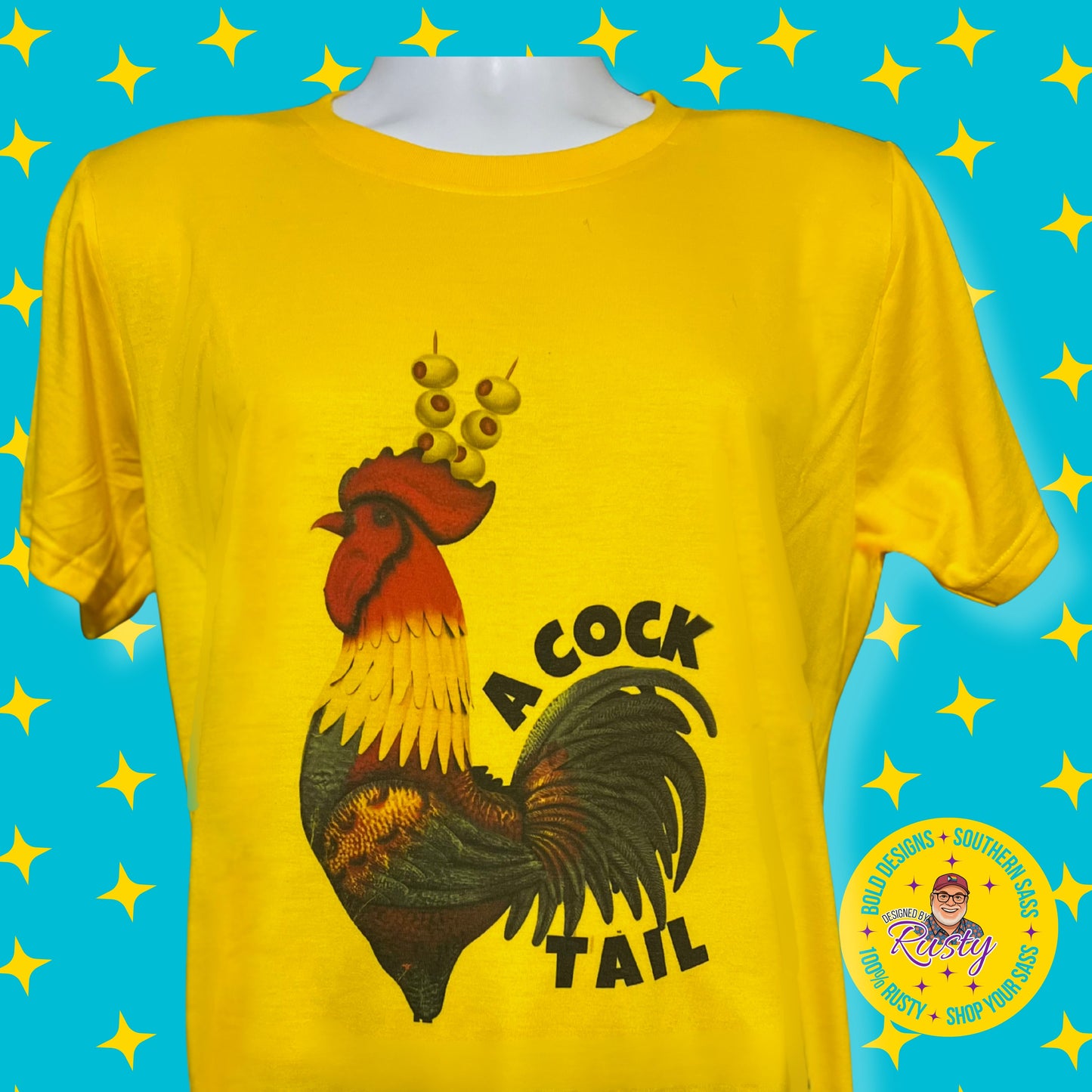 Yellow T-shirt with black rooster illustration wearing olives on toothpicks as a headpiece and the word Cocktail, on a turquoise background with yellow stars and the Designed by Rusty logo.