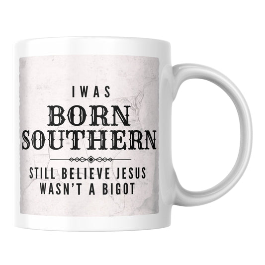 Primary: White ceramic mug with "Jesus Wasn't a Bigot" design on white background. Secondary: White ceramic mug with design on turquoise branded background with stars and DBR logo. Lifestyle: White ceramic mug displayed on a kitchen counter.