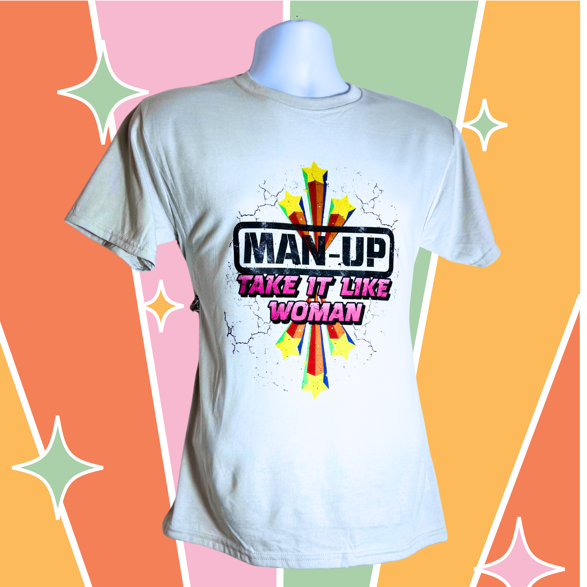 White unisex t-shirt with starburst design and “Man Up – Take It Like a Woman” text, displayed against retro rainbow geometric backdrop.