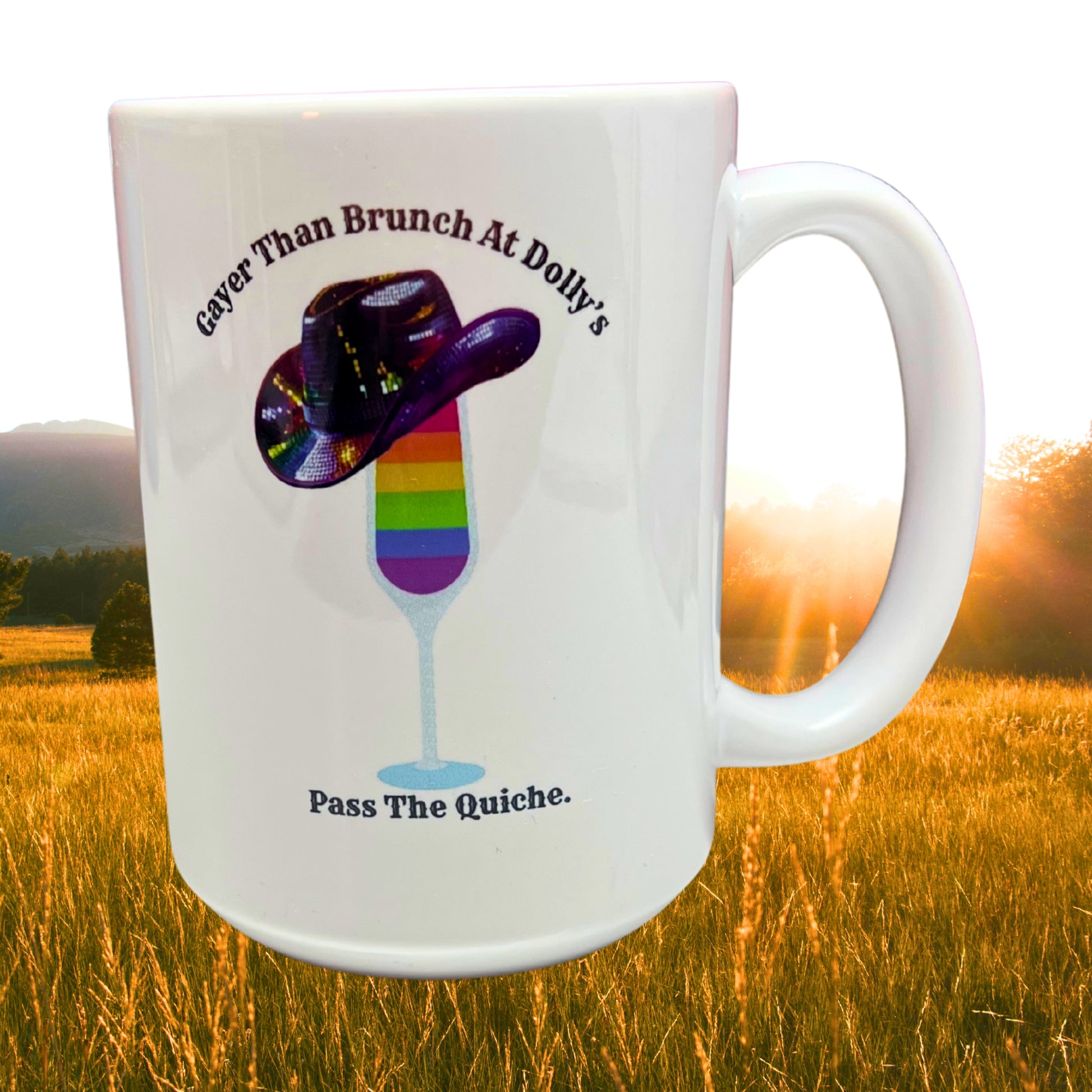 White 15 oz ceramic mug with rainbow mimosa and sequin cowboy hat design, displayed outdoors in a sunny field at sunrise.