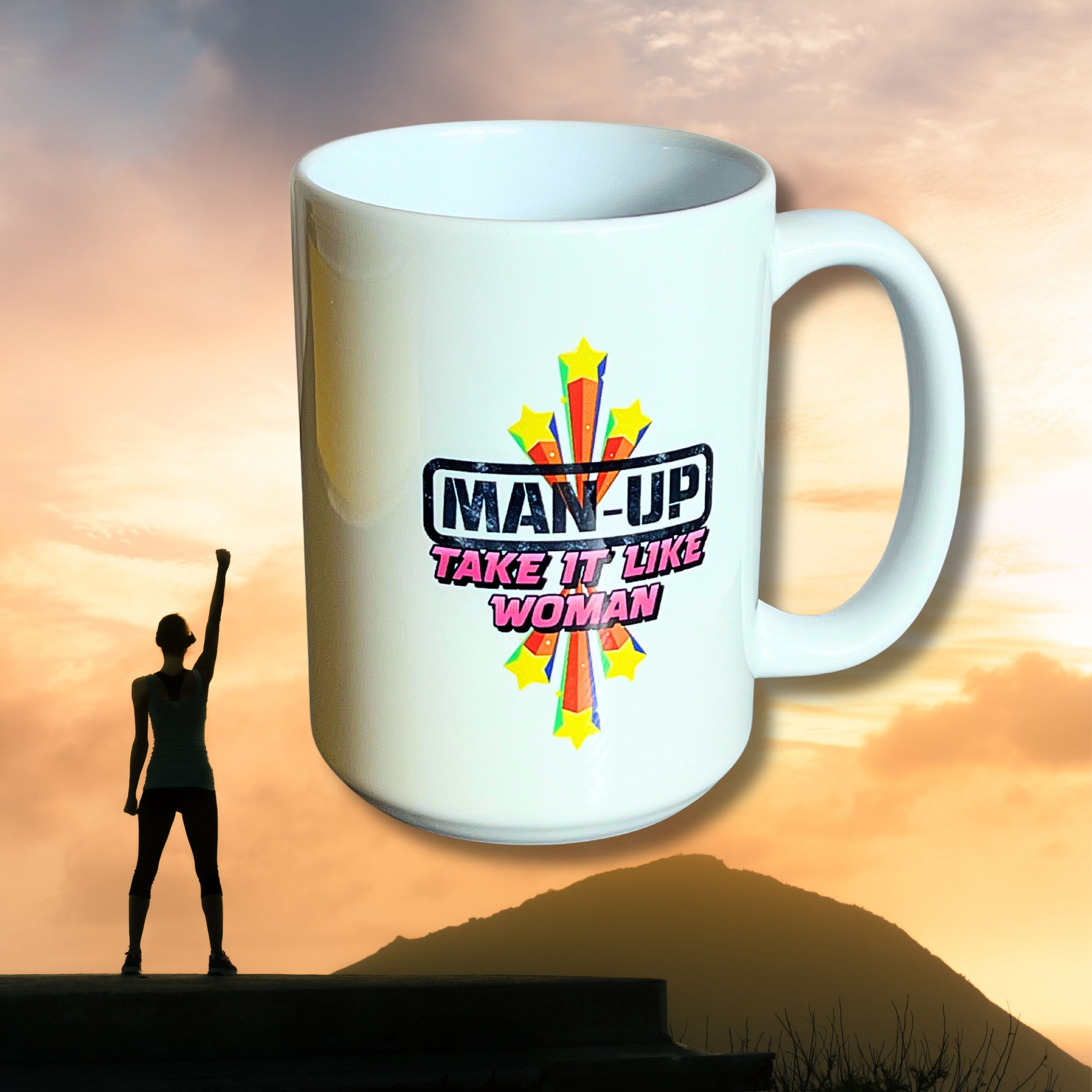 White 15 oz ceramic mug with starburst design and “Man Up – Take It Like a Woman” text, displayed in front of sunrise with silhouette of woman raising fist.