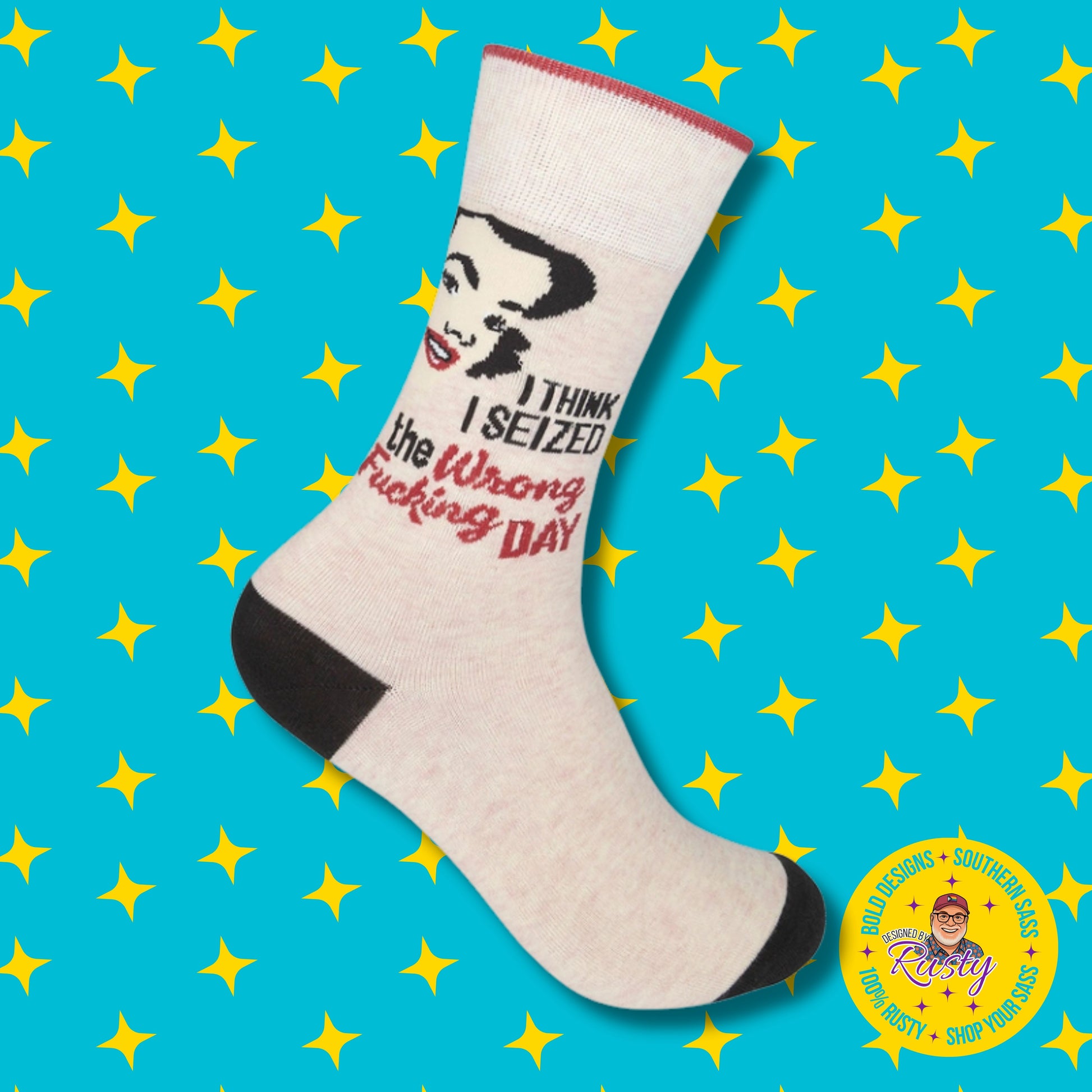 Cream novelty crew socks with retro woman graphic and sarcastic quote “I think I seized the wrong fucking day,” on turquoise background with yellow stars and Designed by Rusty logo.