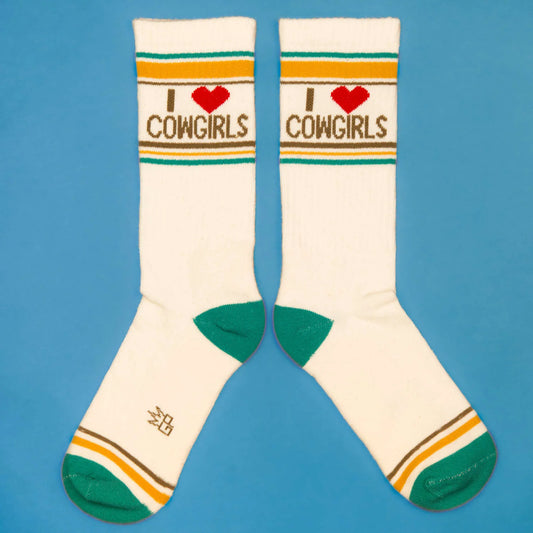 Western-themed socks that say "I ❤️ Cowgirls" in bold brown font, styled with teal and mustard accents on a blue background.