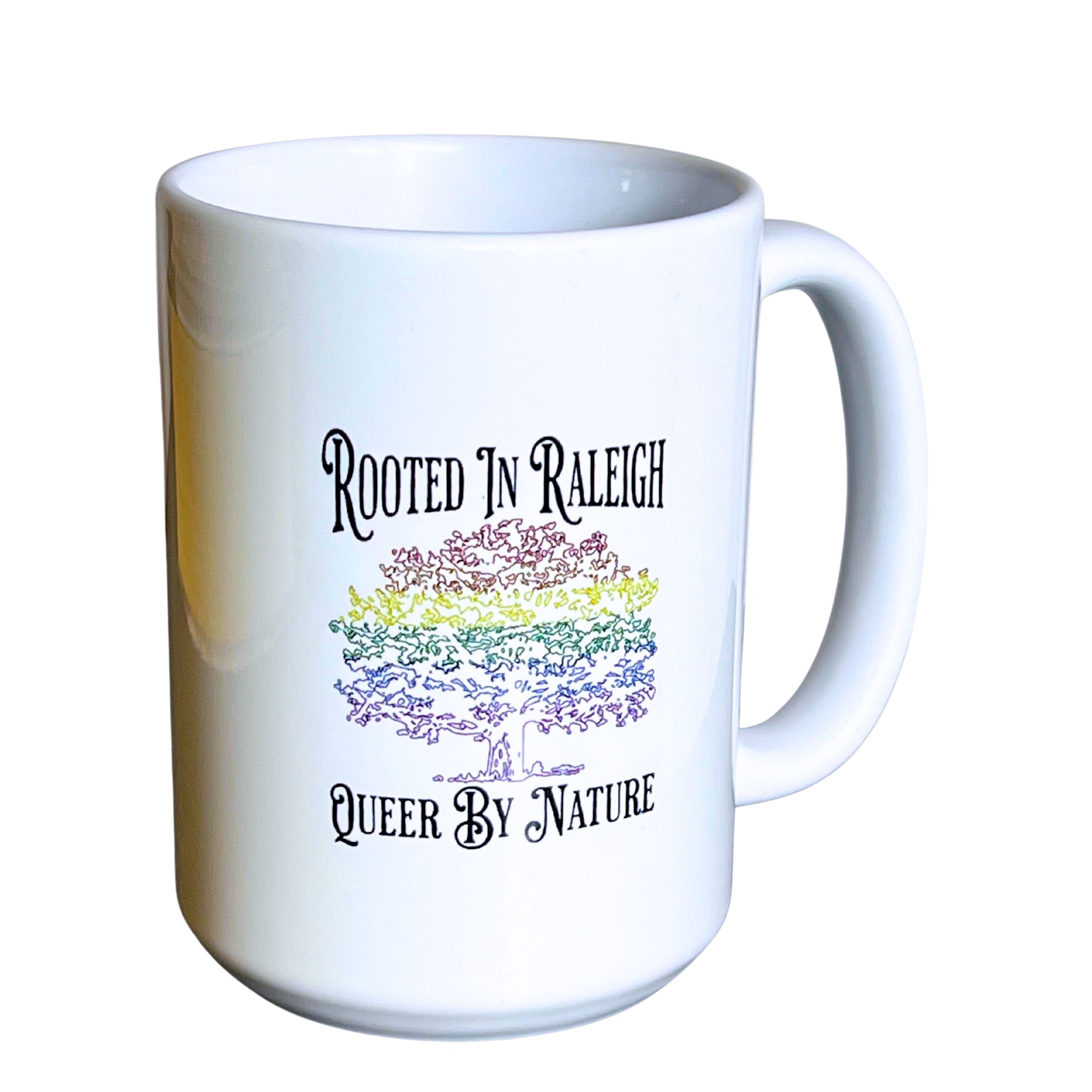 White 15 oz ceramic mug with rainbow oak tree design and text “Rooted in Raleigh – Queer By Nature,” on plain white background.