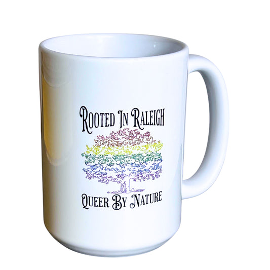White 15 oz ceramic mug with rainbow oak tree design and text “Rooted in Raleigh – Queer By Nature,” on plain white background.