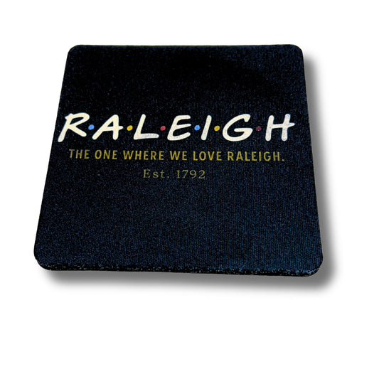 Black coaster with white 'Raleigh' text in Friends-inspired font and tagline 'The one where we love Raleigh. Est. 1792.'