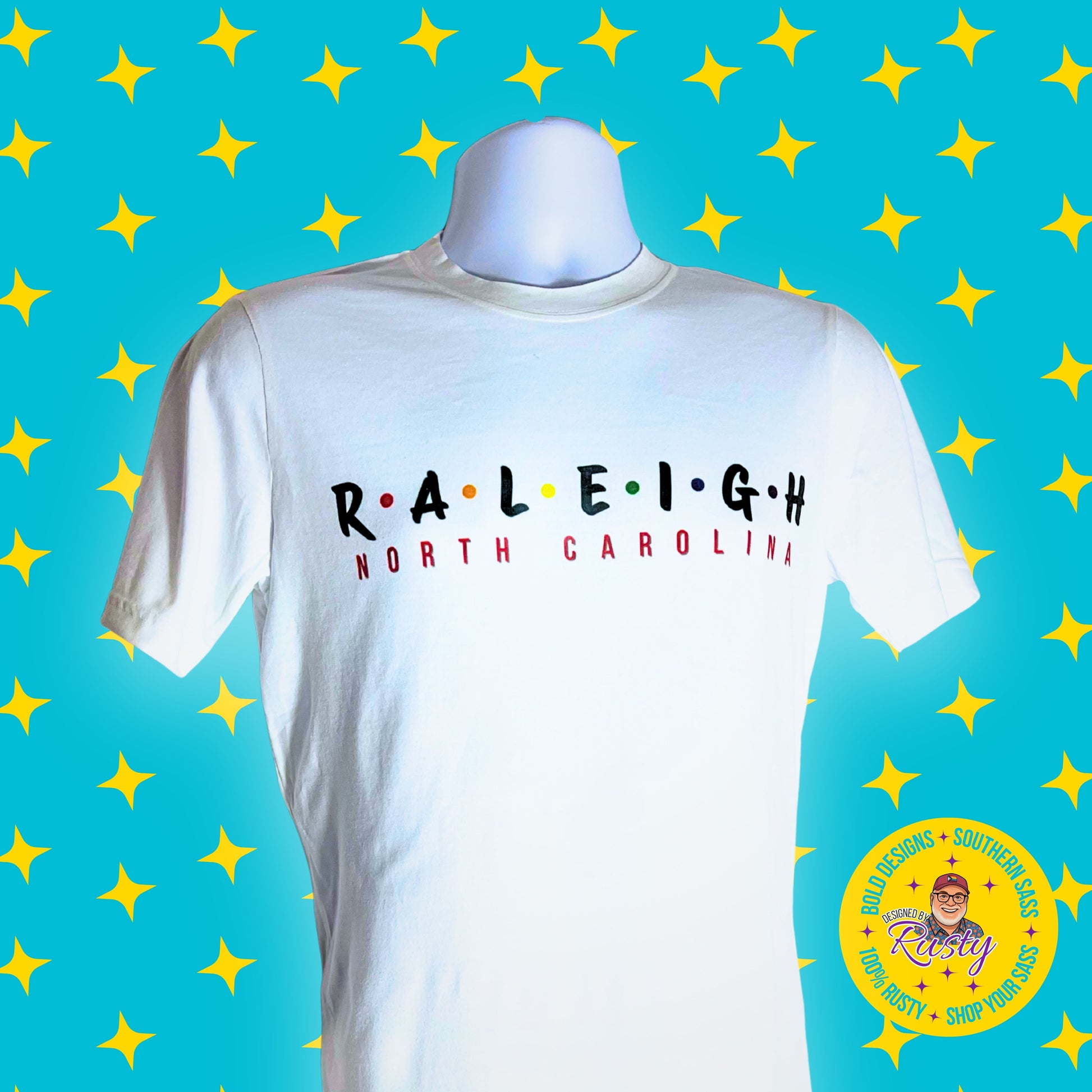 White t-shirt with 'RALEIGH NORTH CAROLINA' text on a blue background with yellow stars