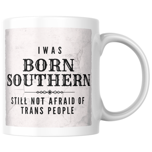 Primary: White ceramic mug with inclusive message on white background. Secondary: White ceramic mug with design on turquoise branded background with stars and DBR logo. Lifestyle: White ceramic mug held in hands in a cozy sweater setting.