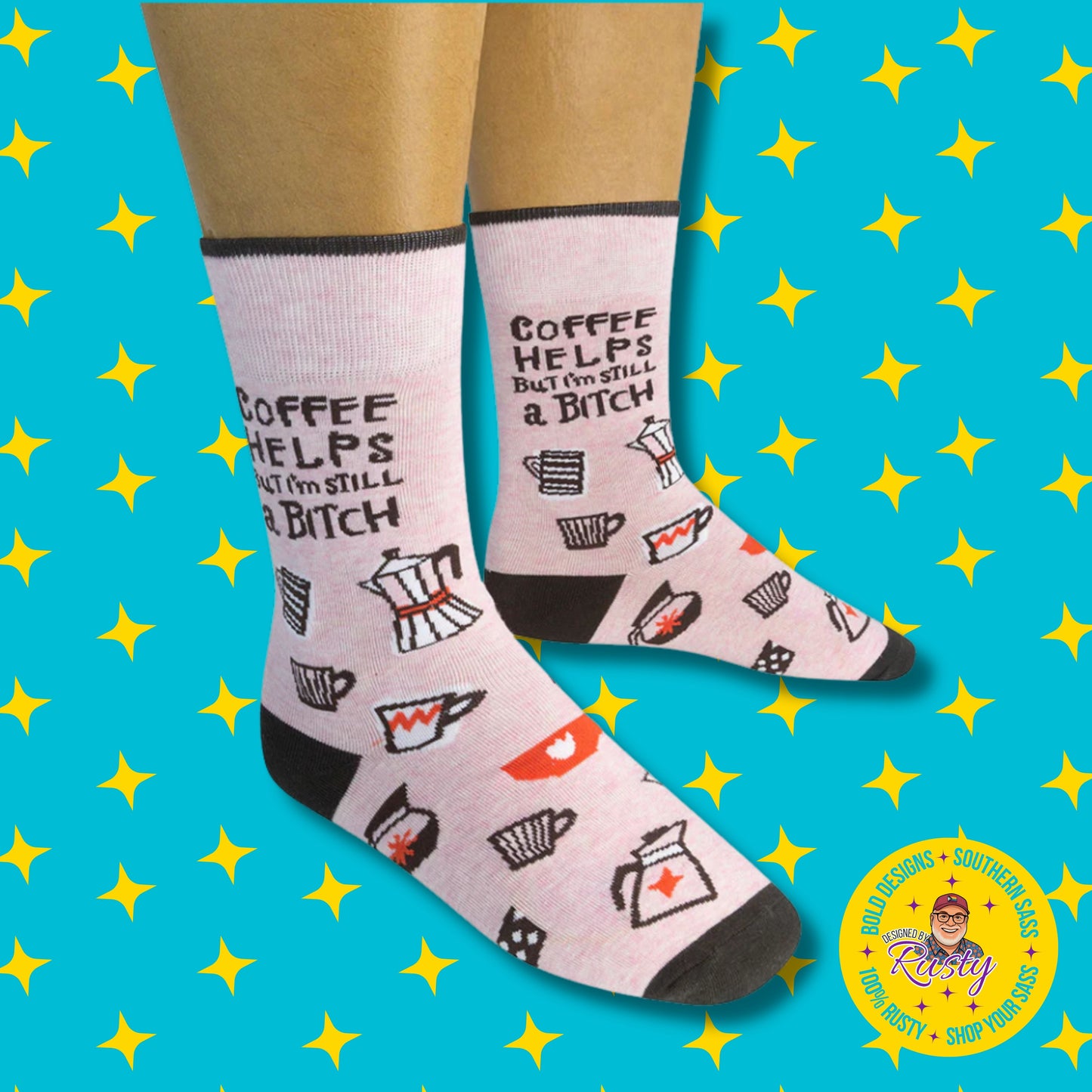 Light pink novelty crew socks with coffee cup graphics and “Coffee helps but I’m still a bitch” text, on turquoise background with yellow stars and Designed by Rusty logo.